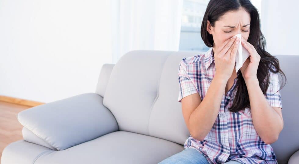 brunette sneezing on tissue on couch