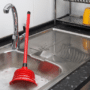 A plunger floating in a clogged sink