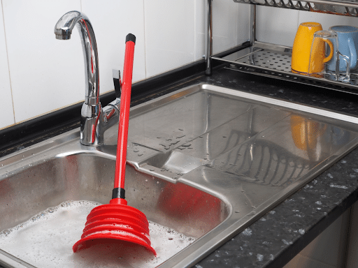 A plunger floating in a clogged sink