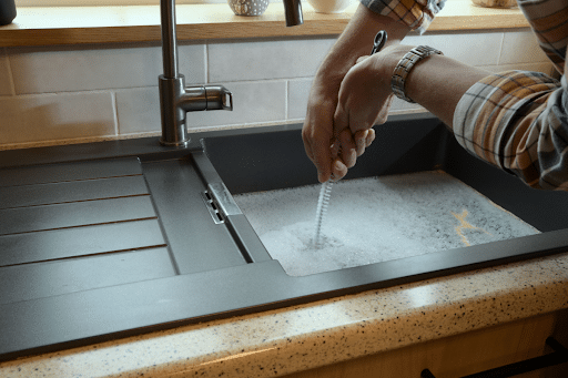 A homeowner trying to unclog an overflowing kitchen sink