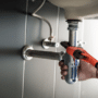 Person performing plumbing maintenance underneath a sink